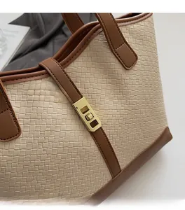 Detailed macro view of beige woven fabric, brown leather trim, and gold twist lock closure