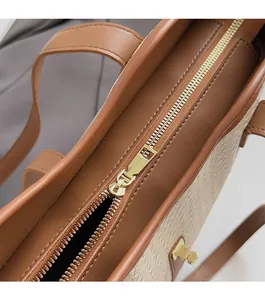 Close-up of smooth gold metal zipper and woven texture on a contrast tote bag