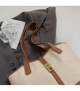 Detail of beige woven tote bag with leather trim, gold hardware and brown shoulder straps