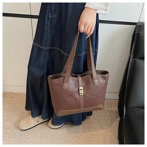 Detail of dark brown woven tote bag with gold metal buckle and smooth PU leather handle