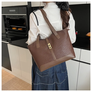 Detail view of woven brown tote bag featuring golden metal clasp and leather handle