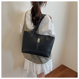 Detail of classic black woven tote bag with metallic fastener shown in shoulder wear style