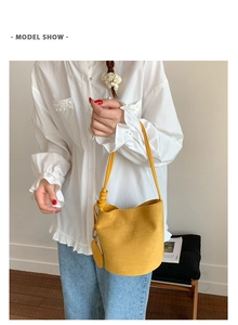 Detail of yellow matte leather bucket bag featuring a knotted handle and round tag