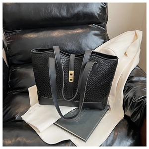 Detail of black woven tote bag featuring a gold rectangle twist-lock and PU leather texture