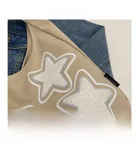 Detailed view of beige canvas tote bag with a white plush star patch and side logo label