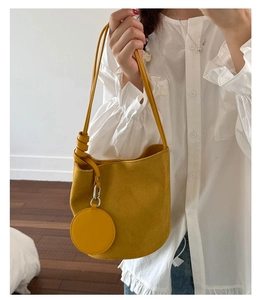 Detail of yellow nubuck bucket bag with decorative knot and matching round coin purse