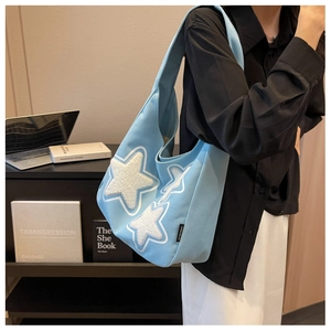 Close-up of light blue canvas hobo bag featuring soft white fuzzy star patches on shoulder