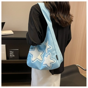 Detail of light blue hobo bag with white plush star patches worn over the shoulder