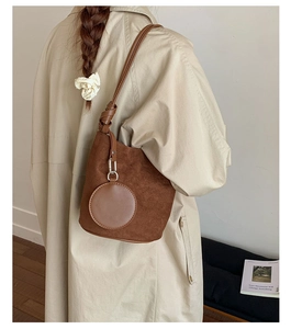 Detail of dark brown suede bucket bag with knot shoulder strap and mini round pouch