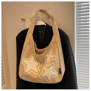 Beige canvas shoulder bag detail featuring three white plush star patches and side tag