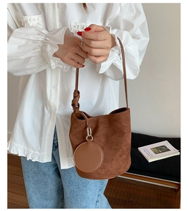 Detail of dark brown suede bucket bag featuring a round coin purse and tied shoulder strap