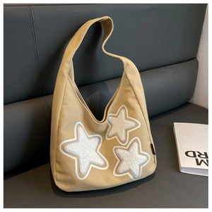 Close-up of khaki hobo shoulder bag featuring three plush white star appliques on canvas
