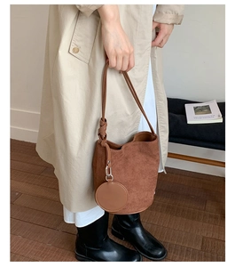 Detail of brown frosted bucket bag with knotted shoulder strap and round coin purse charm