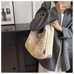 Detail of cream canvas tote bag featuring large star patches and black MIDUOLAI label
