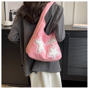 Pink canvas shoulder bag featuring three plush star patches and side brand label