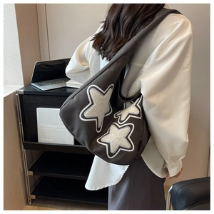 Detail of dark canvas tote bag featuring star patches and spacious interior design
