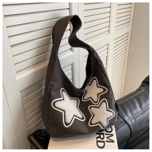 Detail of grey canvas hobo bag featuring three white fuzzy star patches and wide strap