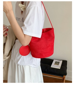 Detail of red matte suede bucket bag featuring long shoulder strap and matching coin purse