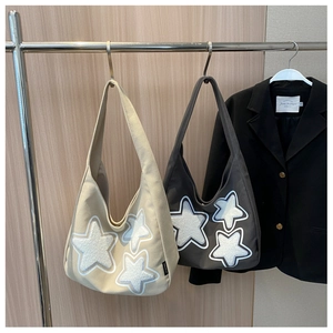 Detail of canvas hobo bags featuring plush star patches and side brand labels