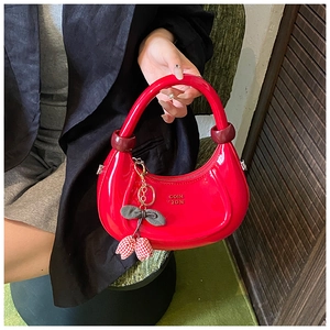 Dettaglio della borsa in pelle verniciata rossa con ciondolo a forma di ciliegia decorativa