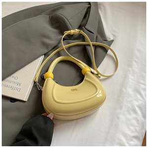 Dettaglio borsa a mezzaluna giallo acceso con perle decorative su sfondo blazer grigio