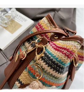 Détail du sac seau tissé coloré avec finitions en cuir marron et ferrures dorées