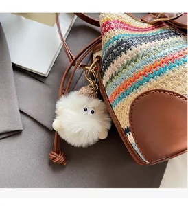 Détail d'un sac seau tissé bicolore avec motifs vagues et breloque oeil en peluche