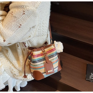Détail du sac seau tissé coloré avec cordon en cuir posé sur des marches en bois