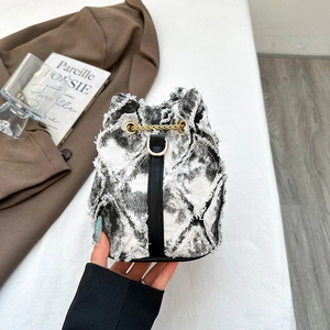 Détail du sac seau tie-dye avec bords effilochés et cordon de serrage en chaîne dorée