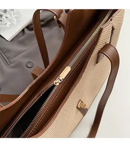 Detailed close-up of smooth gold zipper and premium brown leather trim on woven tote bag