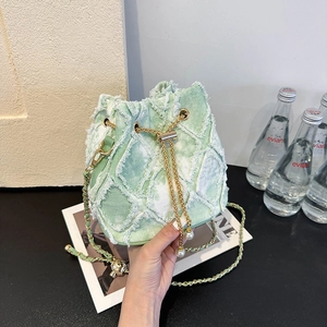 Détail du sac seau en jean vert clair avec chaîne dorée et cordon en perles