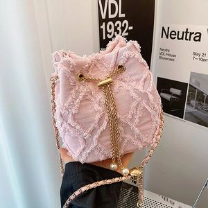 Détail du sac seau en denim rose avec bords effilochés et breloques en perles