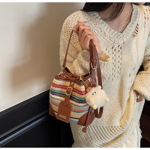Détail du sac seau tissé à rayures multicolores avec bordure en cuir et peluche
