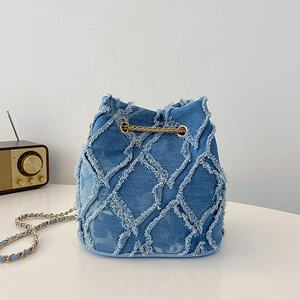 Détail du sac seau en jean matelassé avec bandoulière chaîne dorée et effilochage