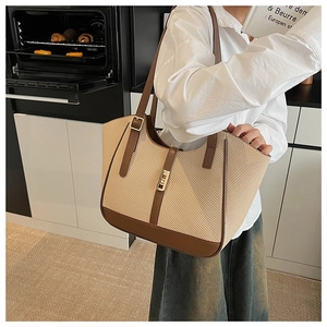 Detail of woven tote bag with brown leather trim and metallic buckle closure