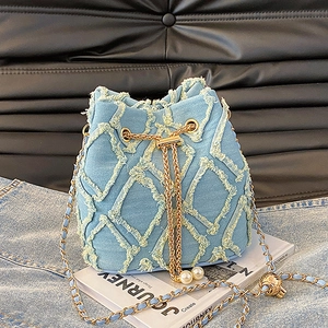 Détail macro du sac seau en jean avec texture effilochée et cordon de serrage perle
