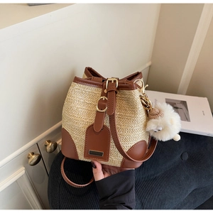 Détail du sac seau en paille avec bordure en cuir marron et breloque mouton