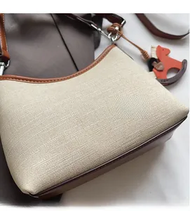 Detailed close-up of beige canvas texture and brown leather trim with a horse charm