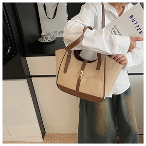 Detail of woven straw tote bag with brown leather trim and metallic buckle closure