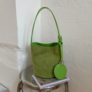 Vibrant green suede bucket bag with slim shoulder strap and minimalist knot detail