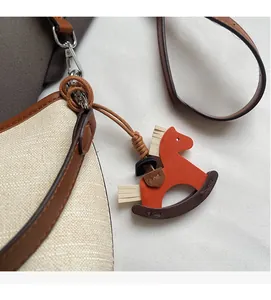 Close-up of canvas bucket bag with leather trim and stylish rocking horse charm