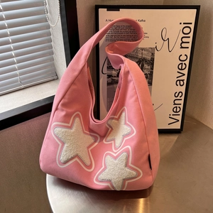 Pink canvas hobo shoulder bag with plush white stars on a modern metal table