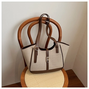 Close-up of the woven tote bag with brown leather handles placed on a wooden chair