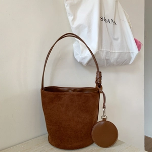 Deep brown matte suede bucket bag with long shoulder strap and round coin purse accessory