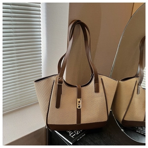 Detailed shot of woven tote bag with brown leather straps and gold twist-lock closure