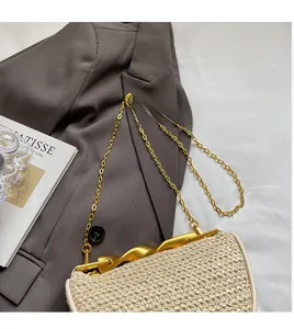 Detail of woven straw handbag featuring gold chunky chain and wavy metal lock closure