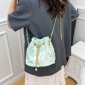 Détail du sac seau vert clair avec matelassage à franges et chaîne en perles
