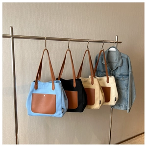 Detail of canvas tote bags in four colors with leather pockets hanging on a metal rack