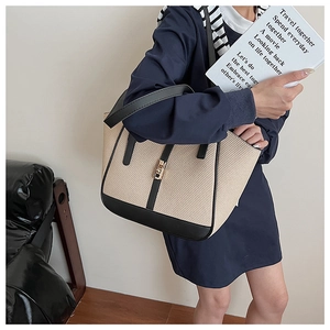 Detail of woven tote bag featuring black leather trim and a golden buckle lock