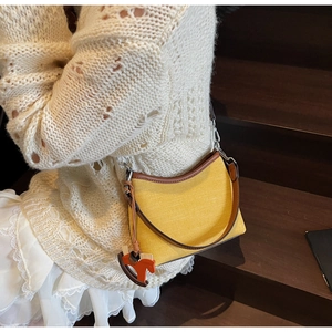 Detailed texture of canvas and brown leather shoulder bag with a horse pendant